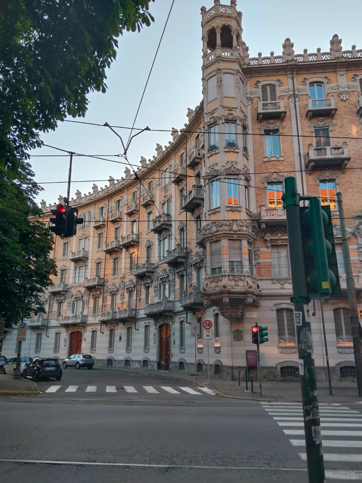Torino'da tramvay telleri, trafik ışığı ve süslü bir köşe apartmanı