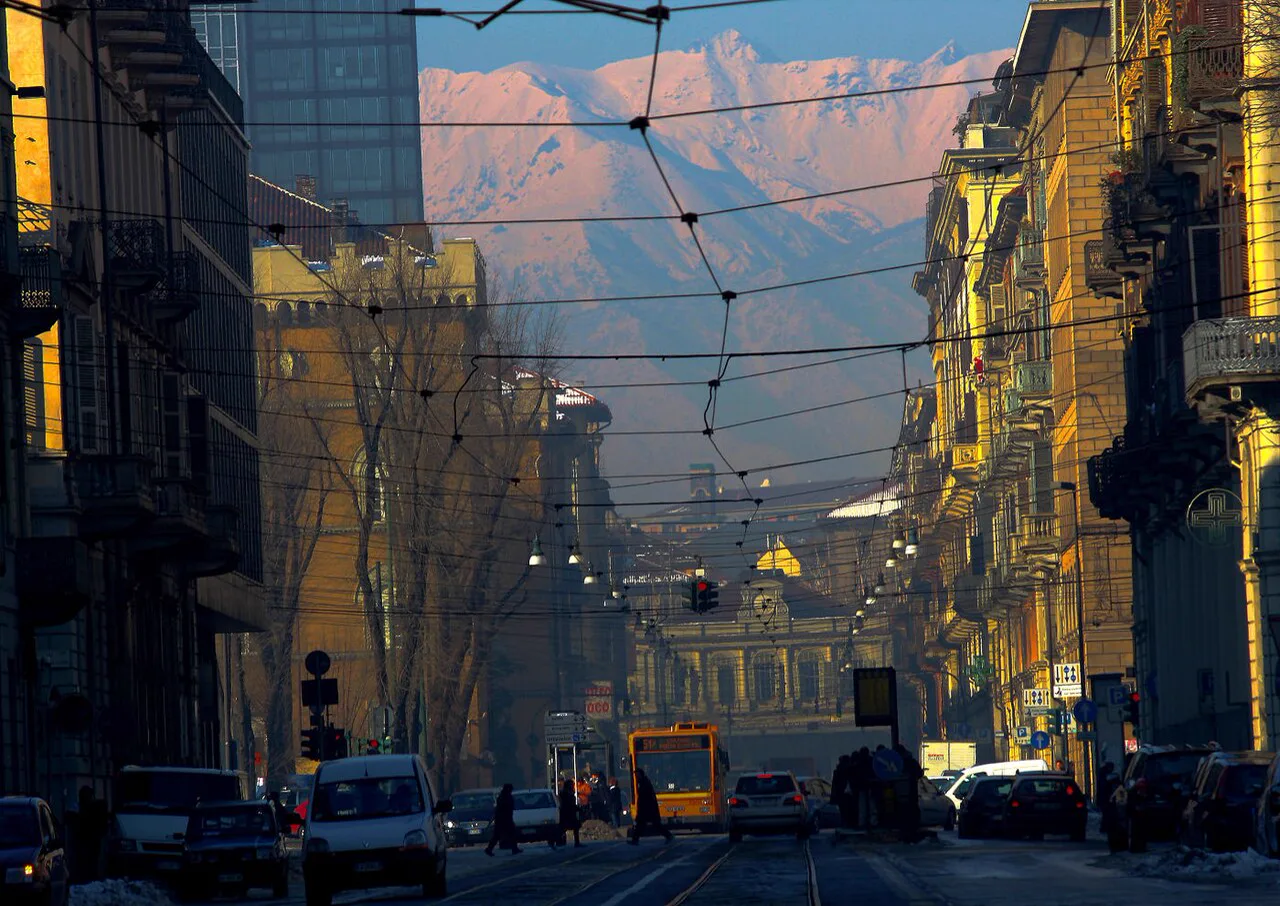 Via Cernaia’nın tramvay hatları, tarihî cepheleri ve arkadaki karlı dağlar