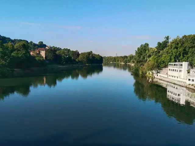 Ağaçlarla çevrili Po Nehri ve suya yansıyan kıyılar