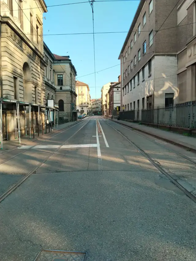 Tramvay rayları ve havai hatlarla uzanan sakin bir Torino sokağı